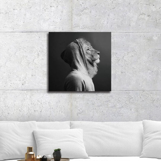 Square wall art measuring 30cm by 30cm, featuring a black and white realistic portrait of a lion wearing a hoodie, set against a grey background. The lion's bold lines and vivid colours create a striking contrast, making this tempered glass print a standout piece for modern or eclectic interiors