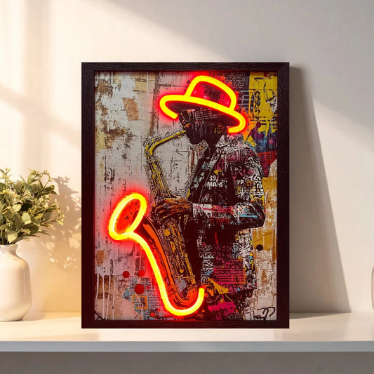 A framed wall art piece leaning on a white shelf, featuring a colorful collage of a saxophone player with bright neon-style red and yellow light shapes. The frame is dark brown, and the artwork includes a hat, jacket, and textured background.