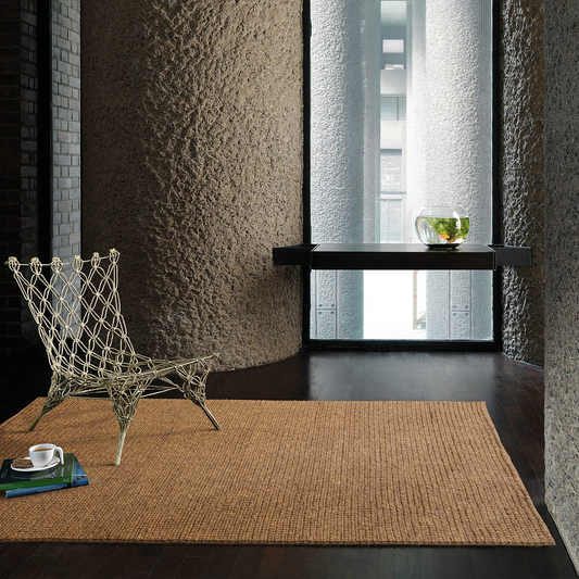 Modern interior with a textured wall, woven chair, and textured rug.