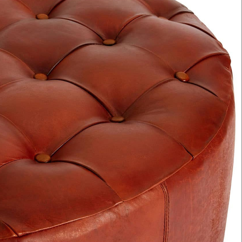 Close-up of a brown leather ottoman with tufted design on a white background