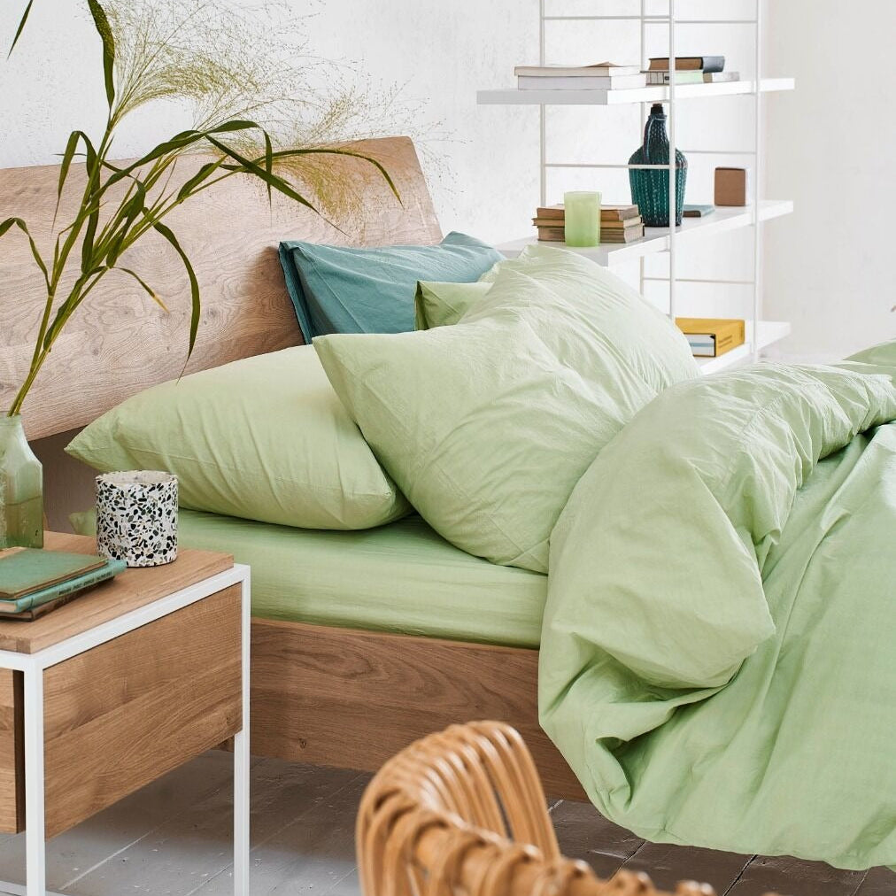Bedroom with green bedding and wooden furniture