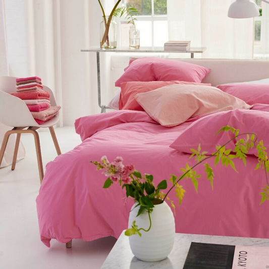 Pink bedroom with a bed, chair, and decor elements.