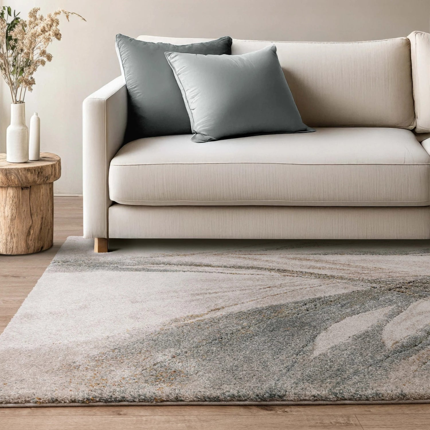Beige sofa with gray cushions on a marble-patterned rug in a living room setting.