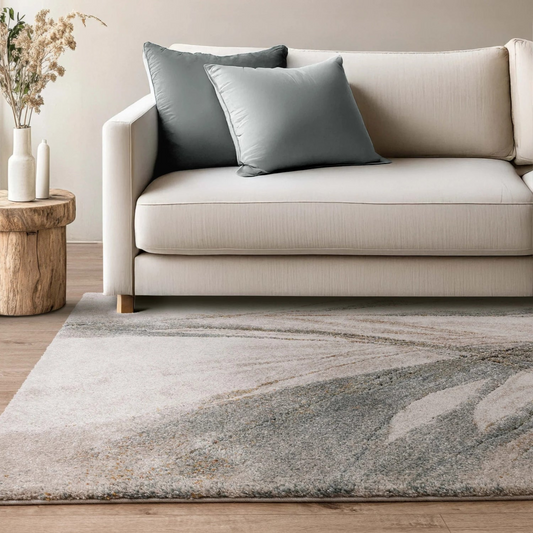 Beige sofa with gray cushions on a marble-patterned rug in a living room setting.