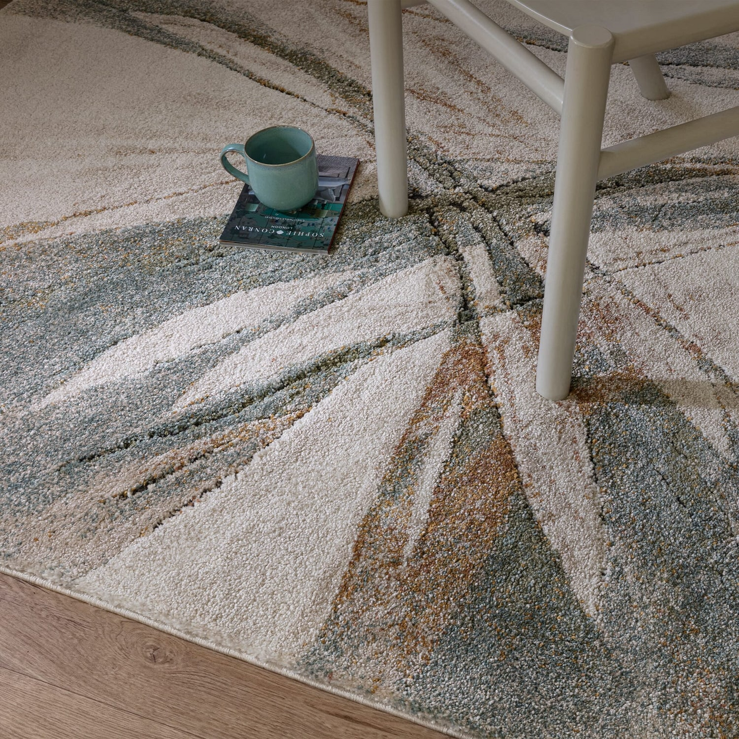 Patterned rug with a chair and a cup on a wooden floor