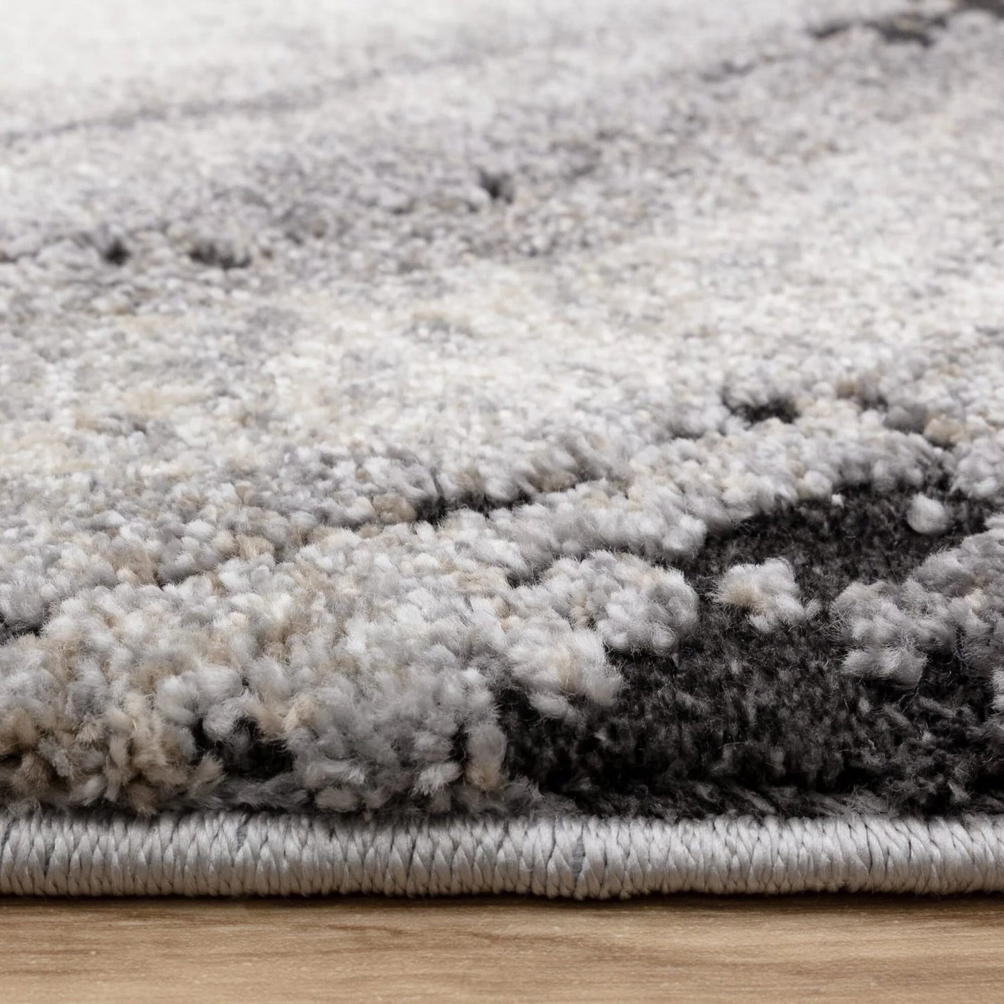 Close-up of a textured gray and white rug on a wooden floor.