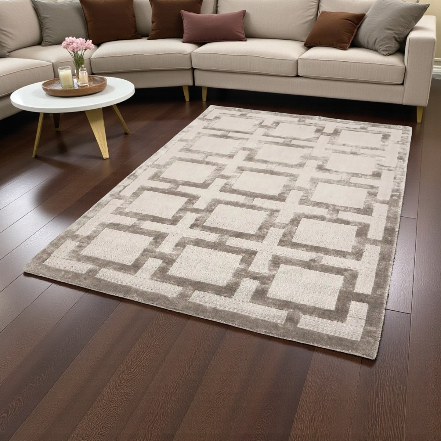 Geometric patterned rug on a wooden floor with a beige sectional sofa in the background.