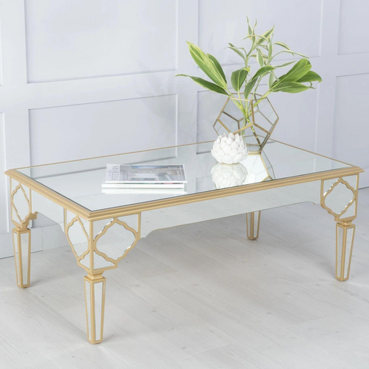 Gold coffee table with a glass top on a white floor and wall background