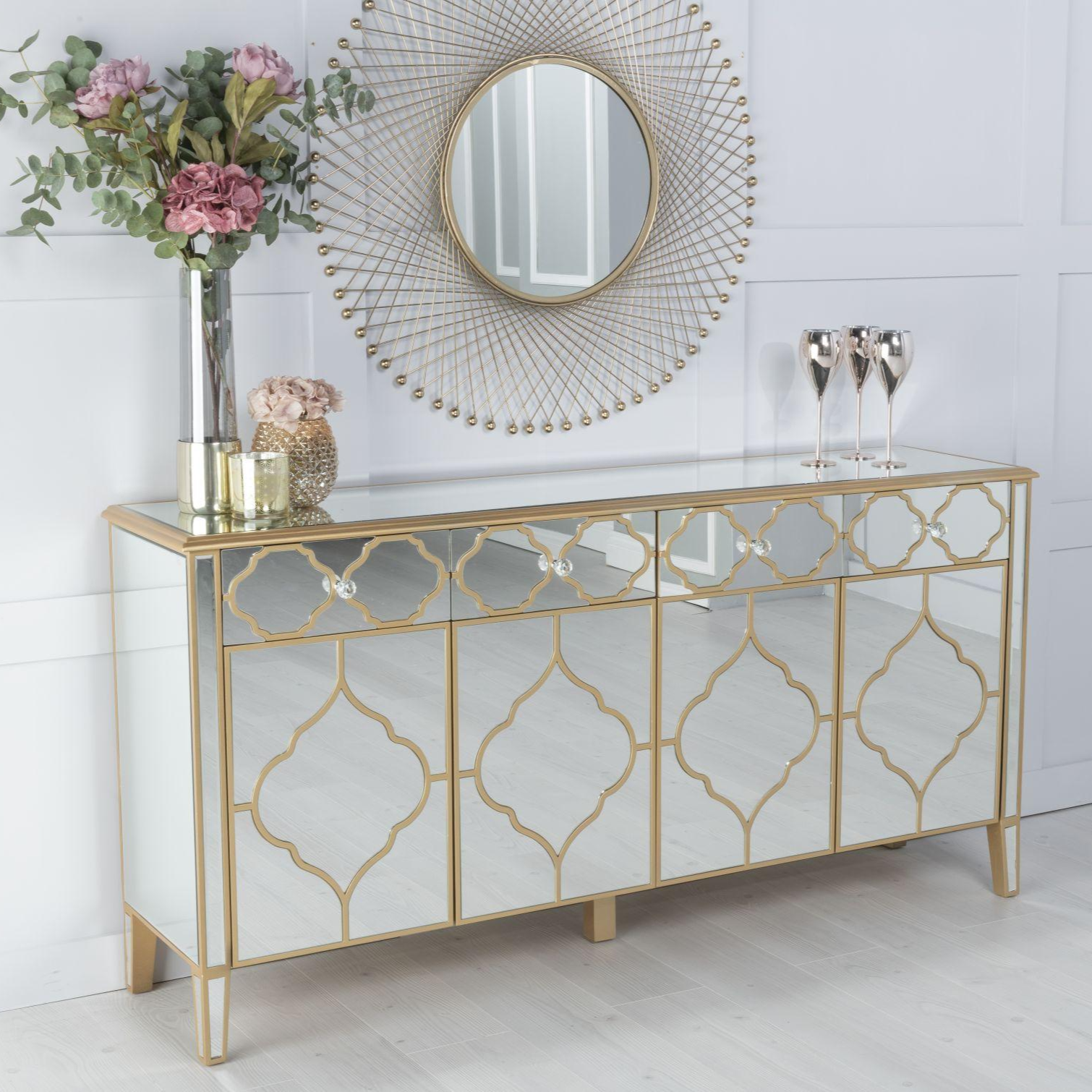 Decorative console table with gold geometric patterns, flowers, and a mirror in a room.