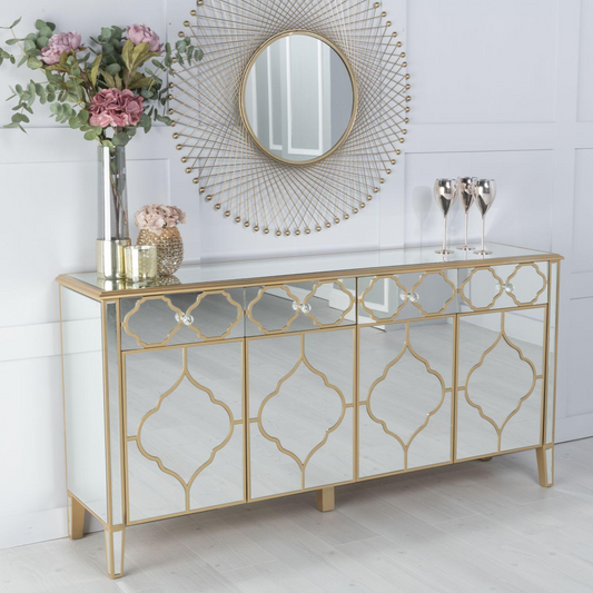 Decorative console table with gold geometric patterns, flowers, and a mirror in a room.