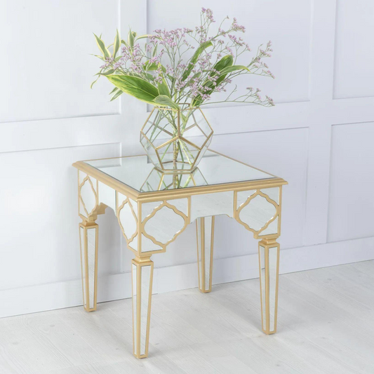 Glass side table with gold legs and a vase of flowers on a white background