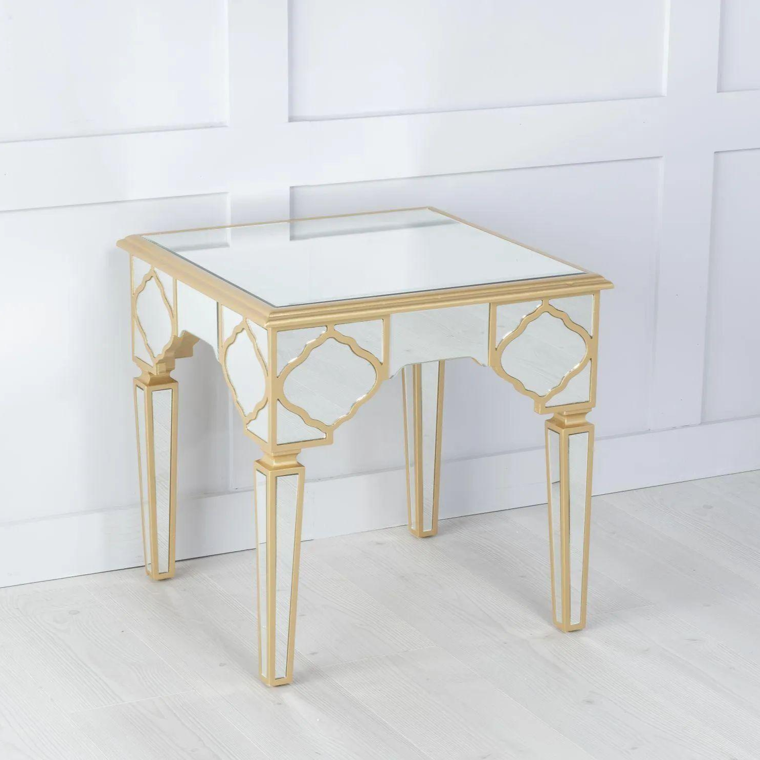 Gold-framed glass table against a white paneled wall