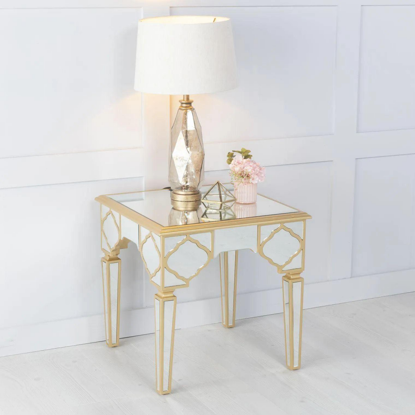 Gold side table with mirror surface and lamp on a white background
