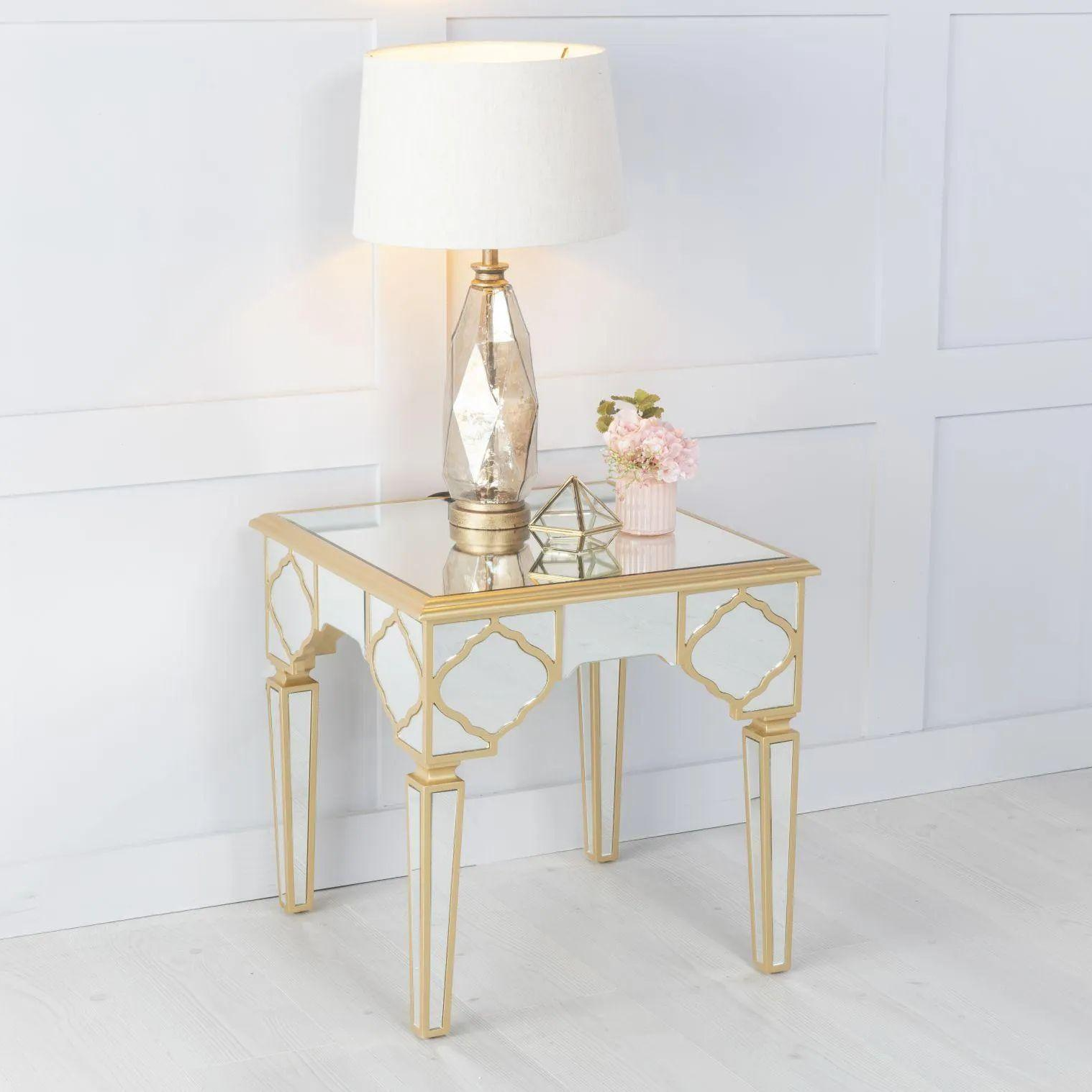 Gold side table with mirror surface and lamp on a white background