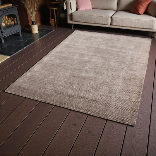 soft brown rug on a wooden floor in a living room setting with a fireplace and sofa.