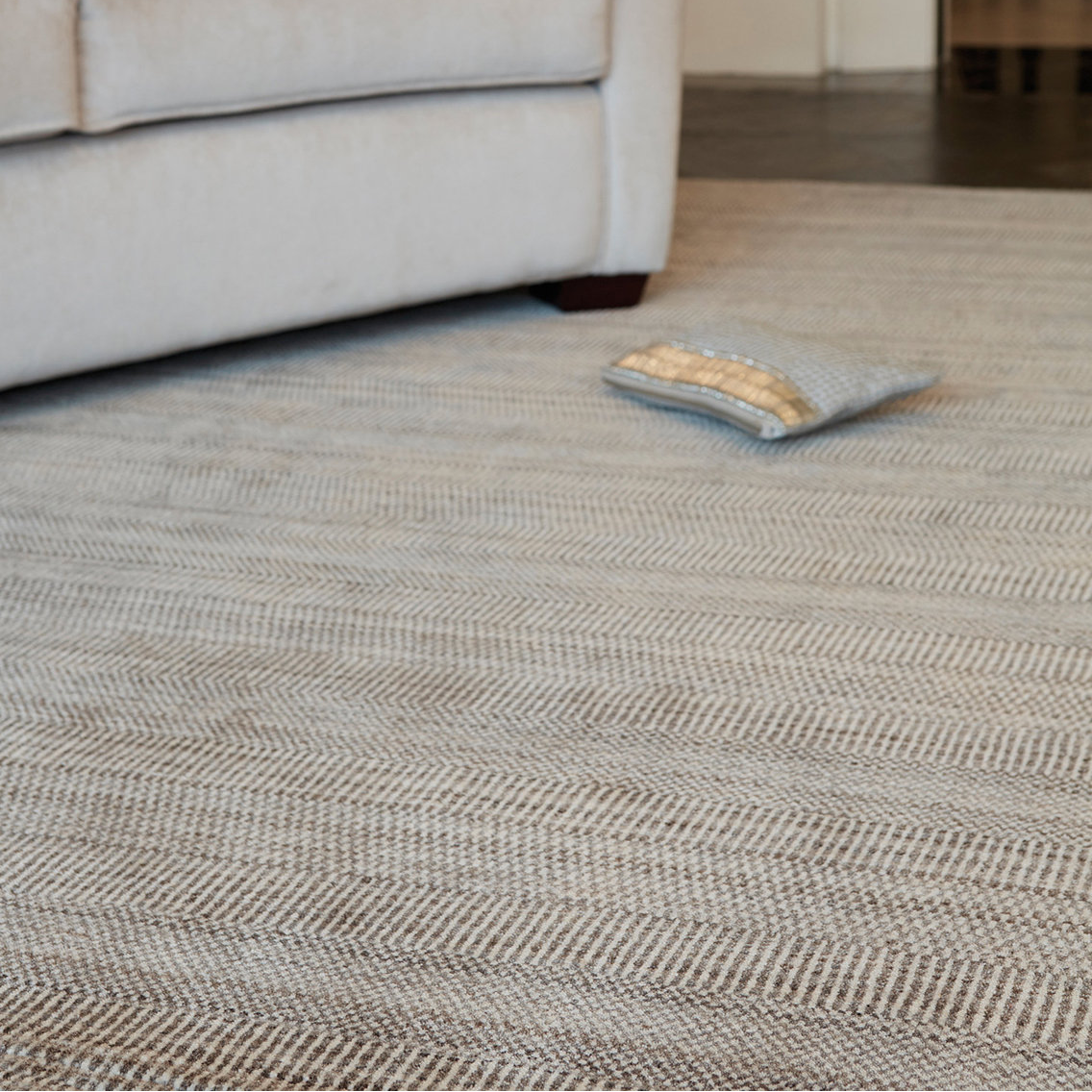 Living room with a textured rug, sofa, and decorative pillow.
