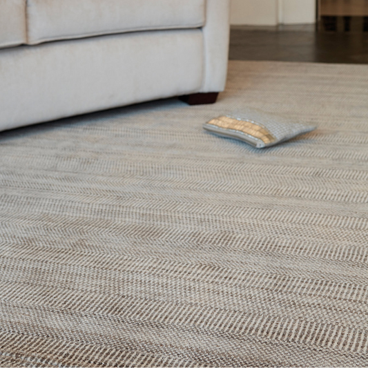 Living room with a textured rug, sofa, and decorative pillow.
