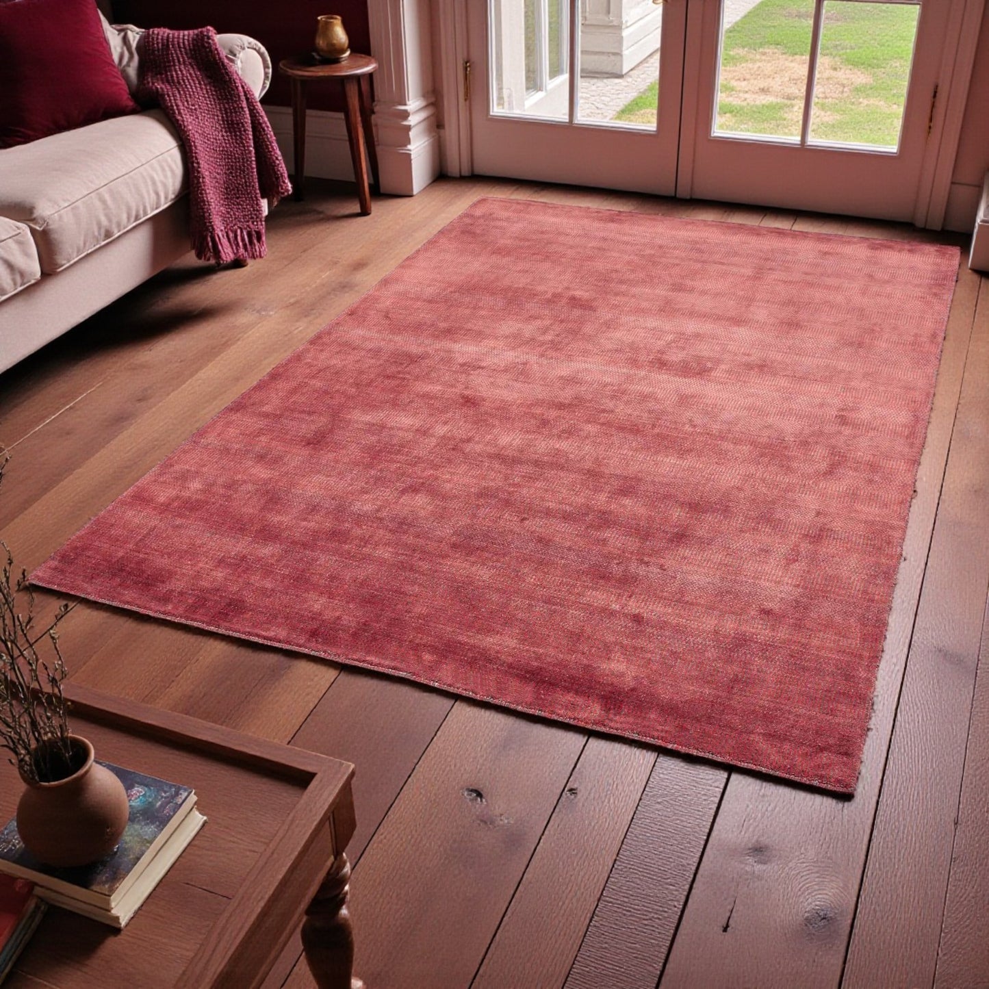 Red rug on a wooden floor in a living room with a couch and coffee table.