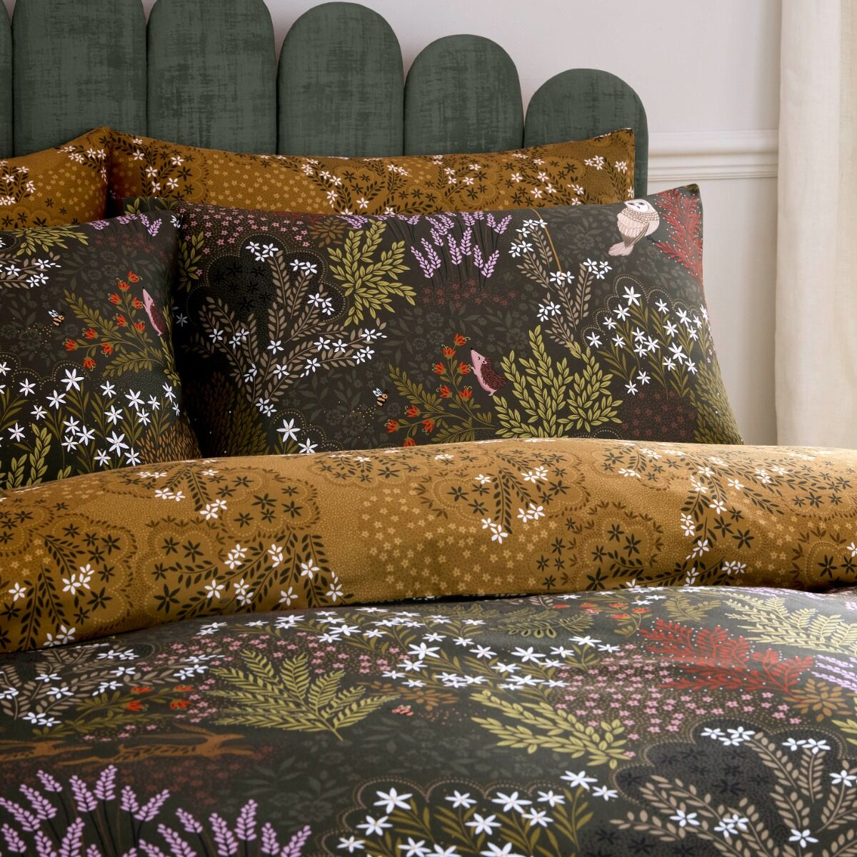 Floral-patterned bedding set with matching pillows on a bed.