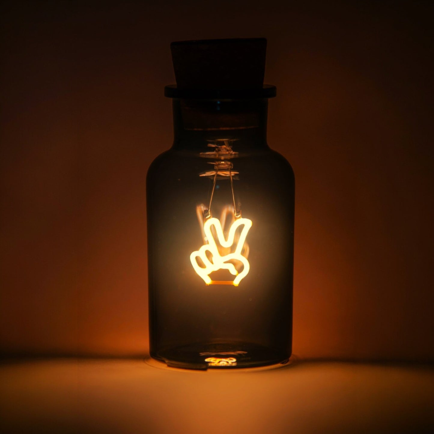 Decorative light bulb shaped like a peace sign inside a dark glass bottle on a dark background