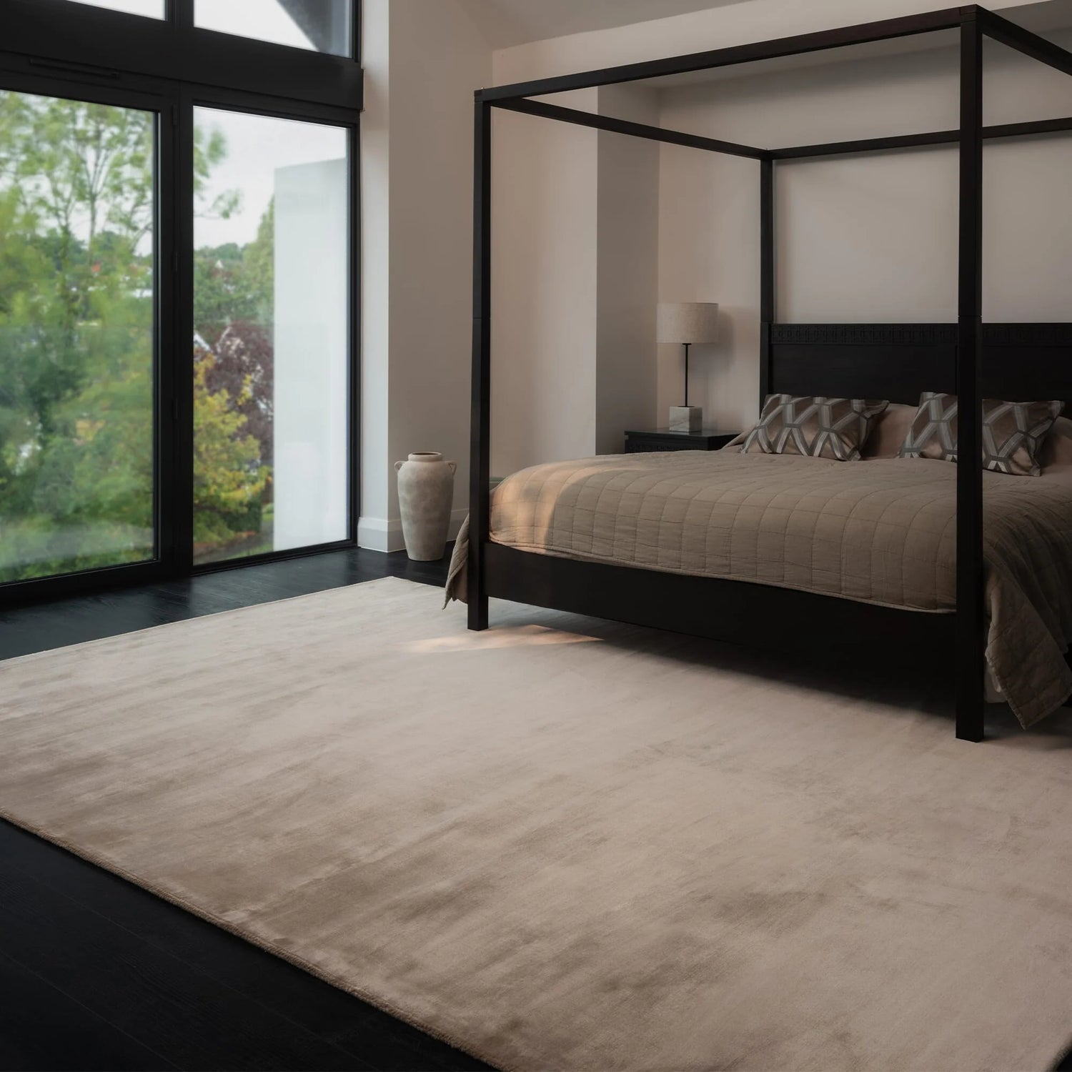 Modern bedroom with a four-poster bed and large windows.