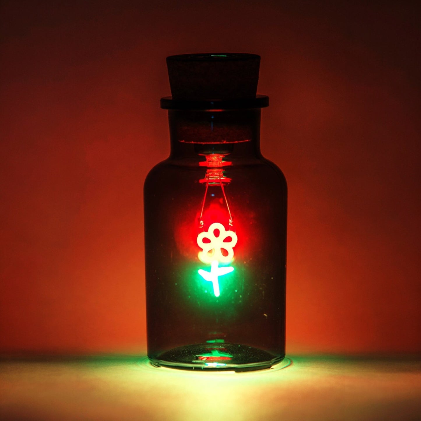 Glass bottle with a floral design light inside against a red background
