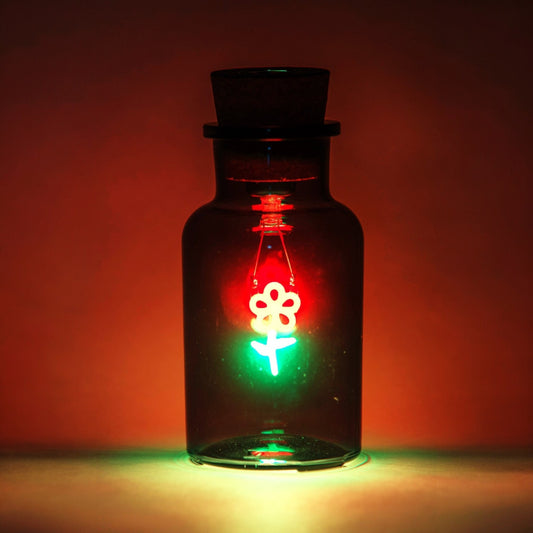 Glass bottle with a floral design light inside against a red background