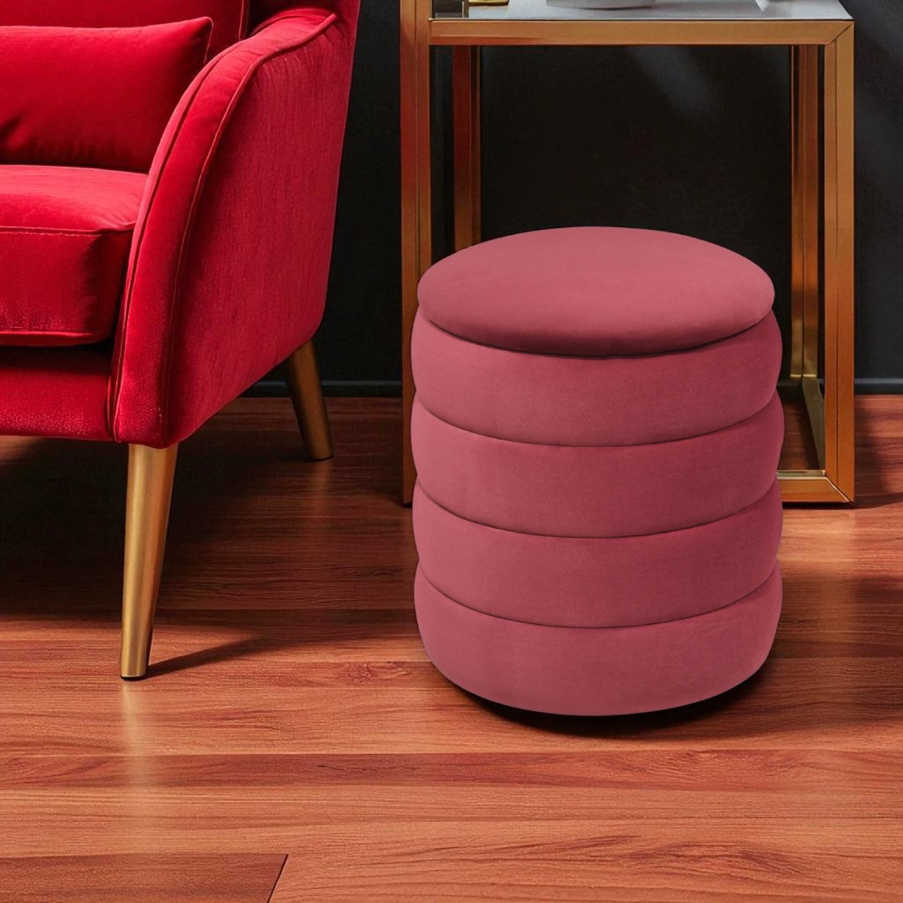 Pink ottoman next to a red armchair on a wooden floor.