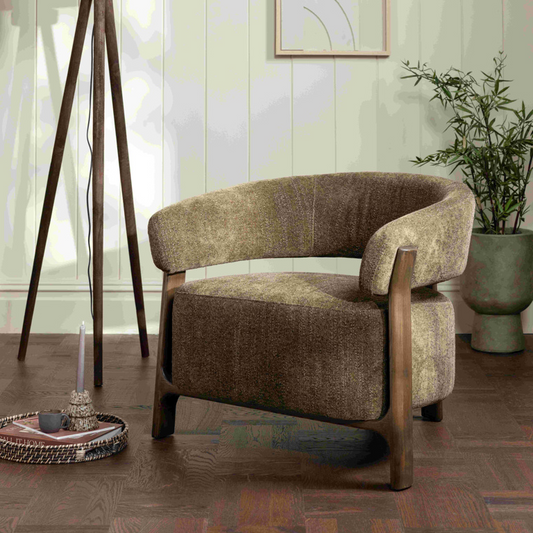 olive green armchair in a room with a lamp, plant, and abstract art on the wall.