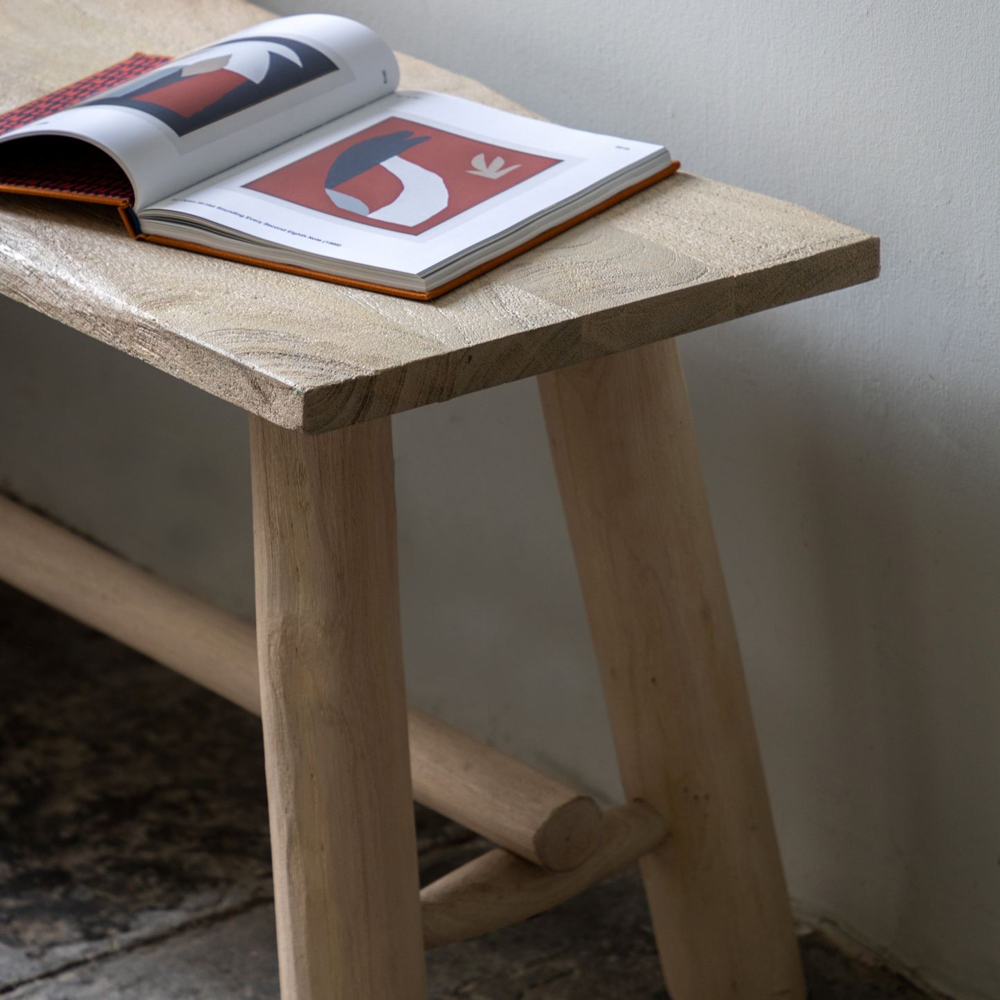 Wooden bench with an open book on a plain background