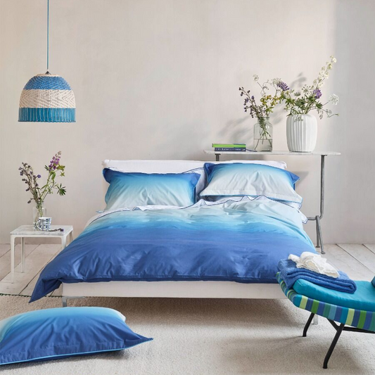 Modern bedroom with blue bedding and decor, featuring a ceiling light fixture.