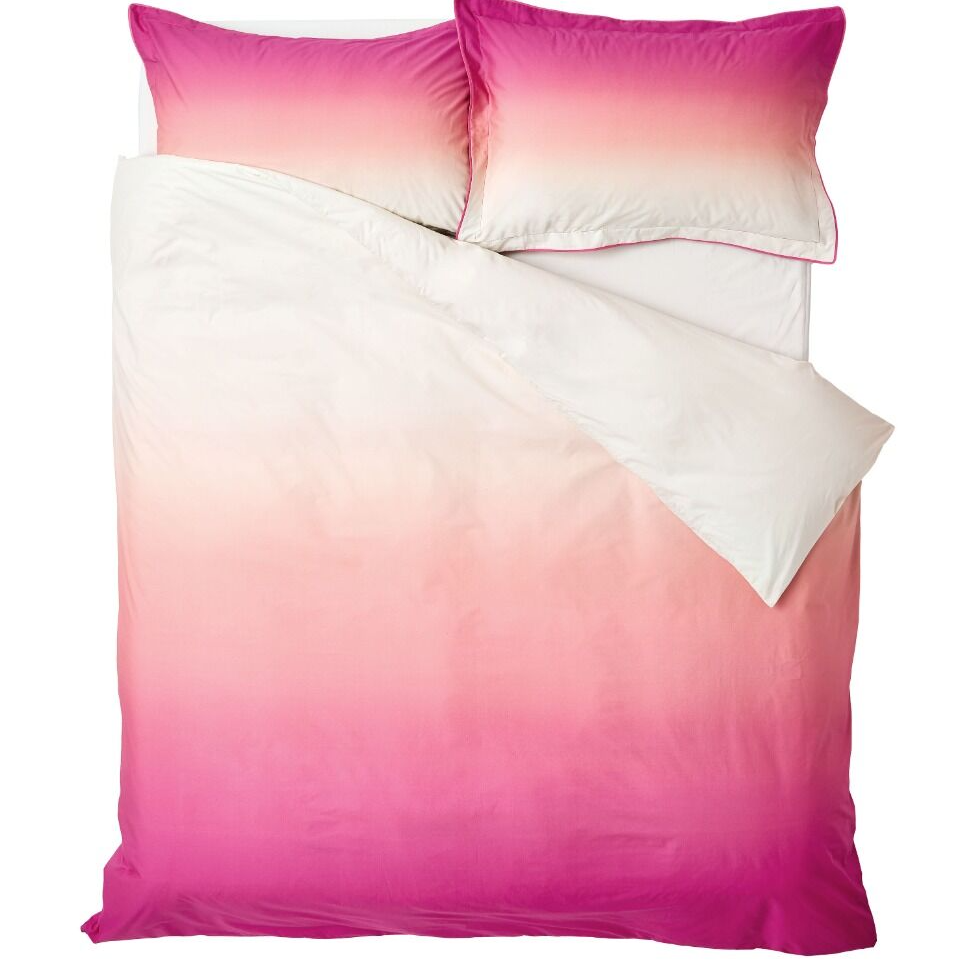 Ombre pink and white bedding set with matching pillows on a white background
