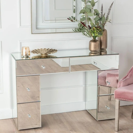 Modern mirrored desk with decorative items in a stylish room.
