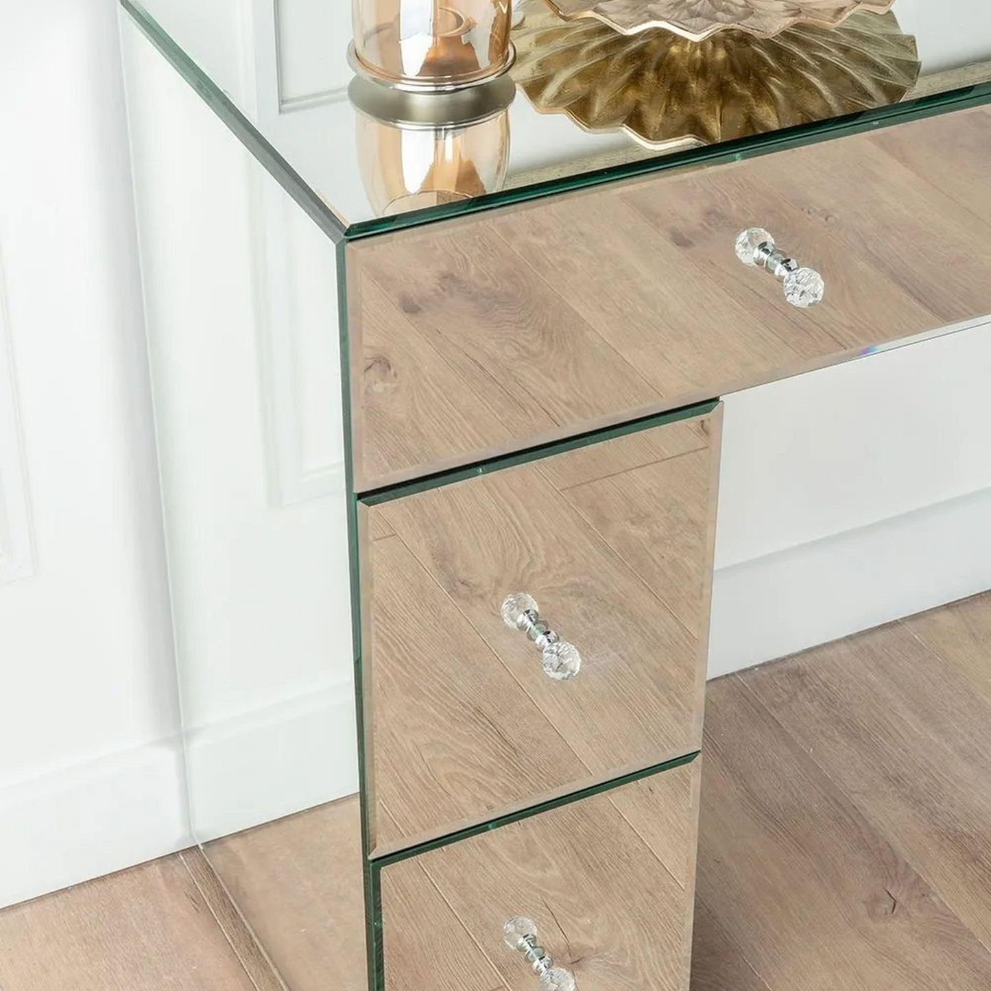Wooden side table with glass top and clear crystal knobs against a white wall.