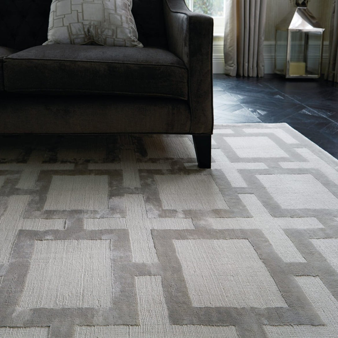 Patterned rug on a wooden floor with a dark sofa in the background