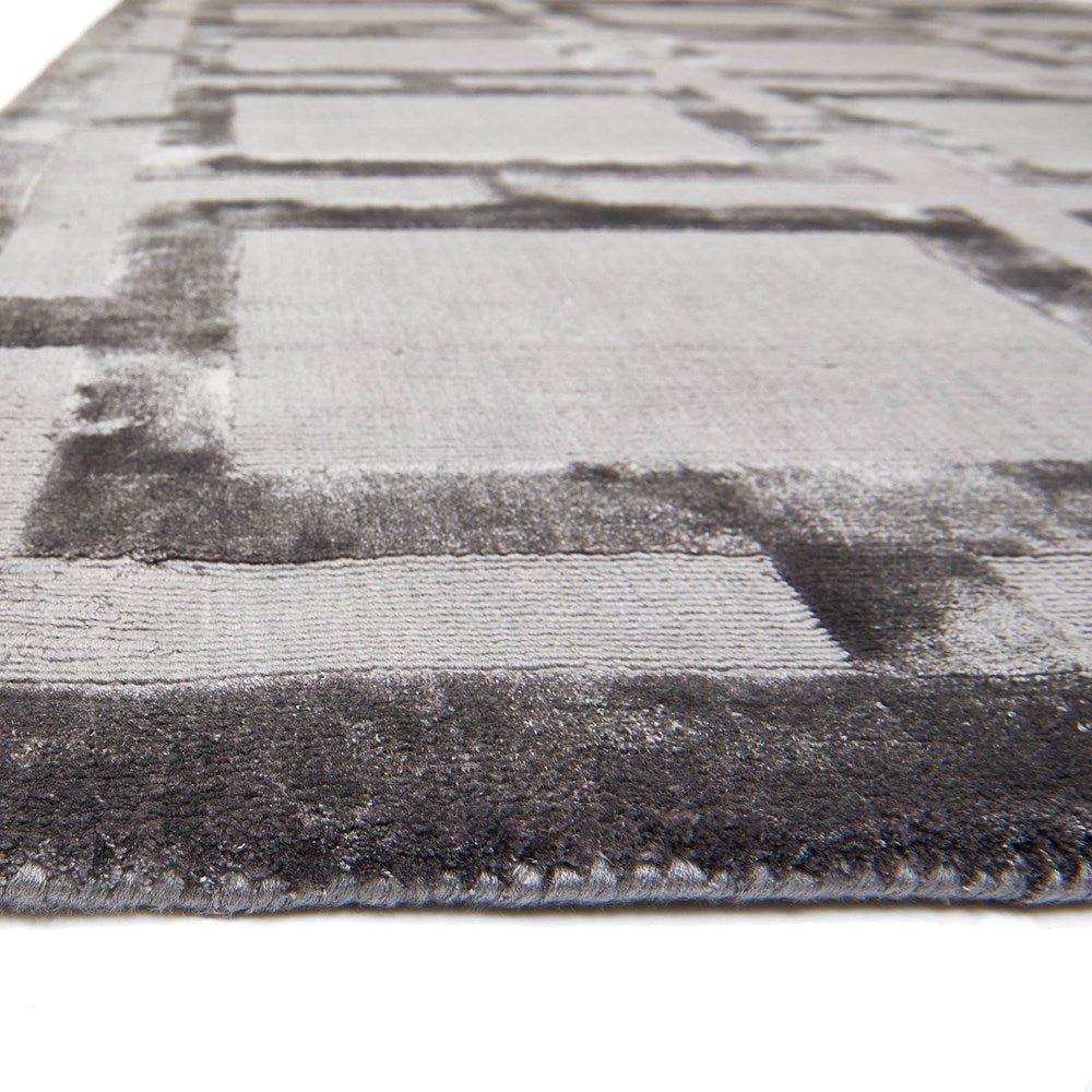 Close-up of a textured gray and black area rug on a light background
