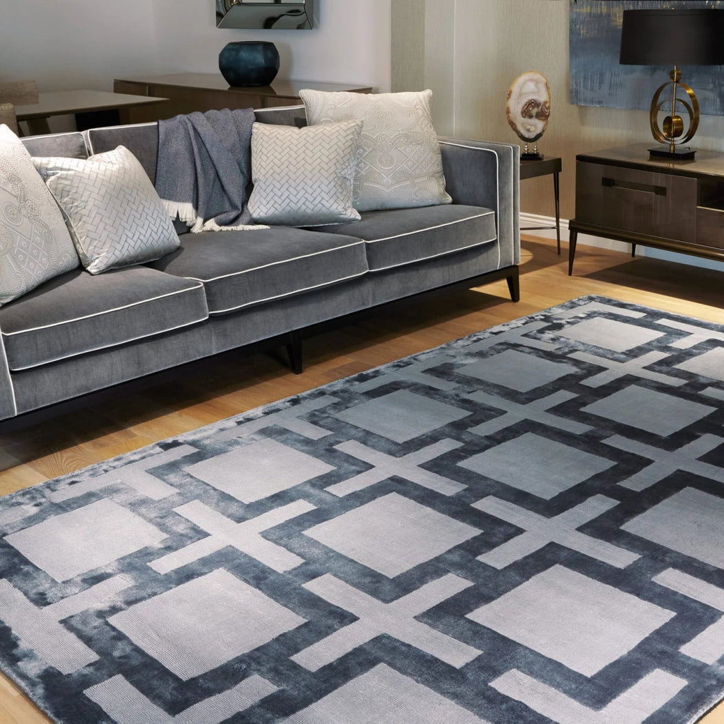 Living room with a gray sofa, geometric blue rug, and wooden entertainment center.