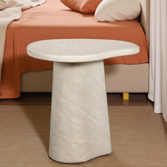 Marble side table in a bedroom setting with orange bedding and neutral walls.