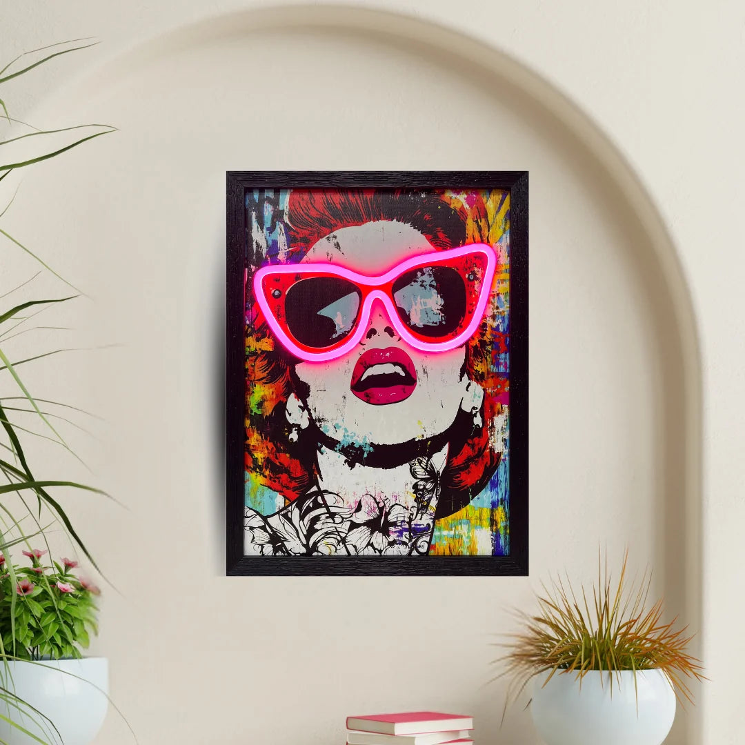 Framed artwork with colorful design and neon pink sunglasses on a wall.