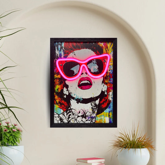Framed artwork with colorful design and neon pink sunglasses on a wall.
