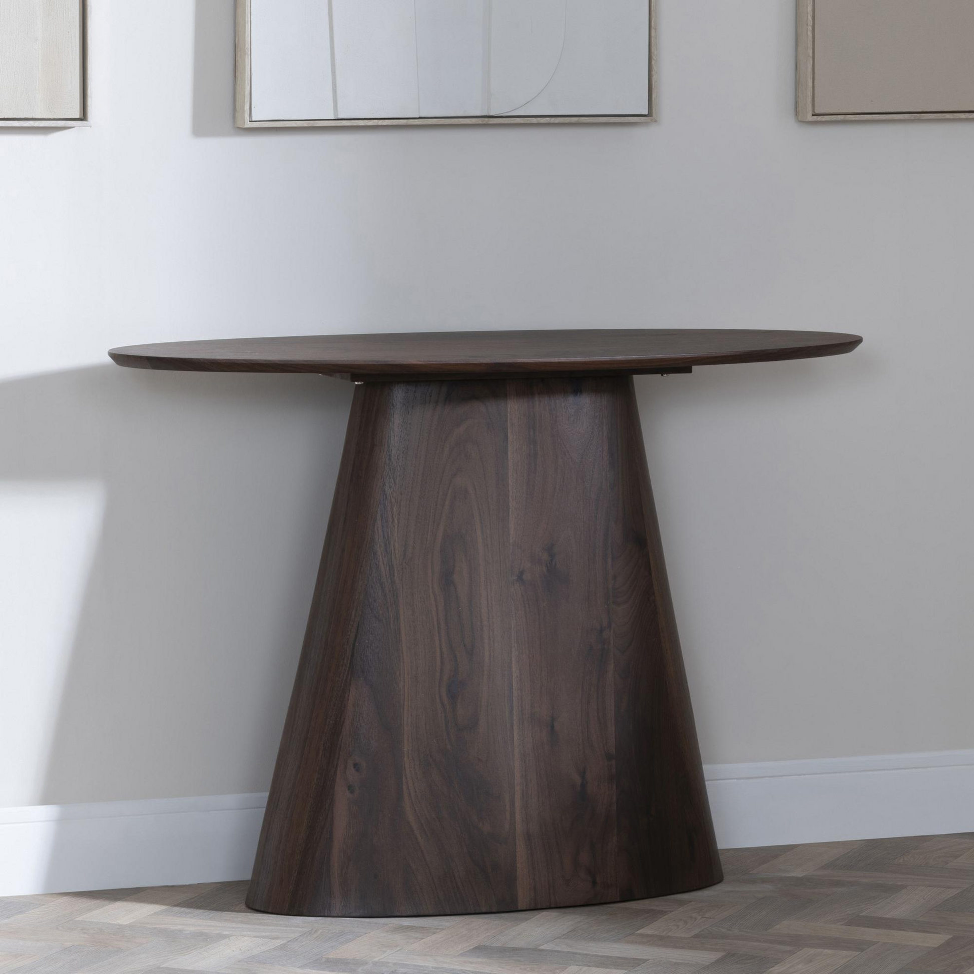 Wooden dining table against a plain wall with light-colored flooring.